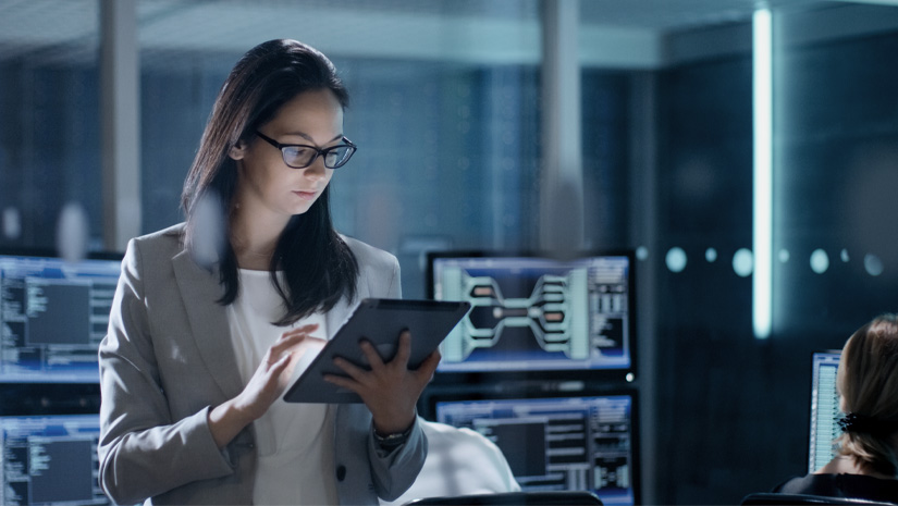 Woman reviewing tablet security screens in background