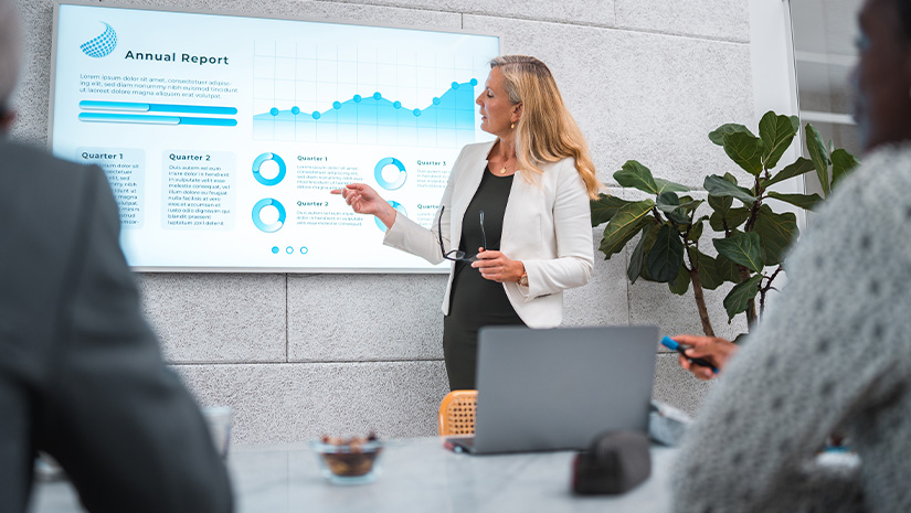 Mature Businesswoman's Expert Presentation in a Modern Boardroom 825x465